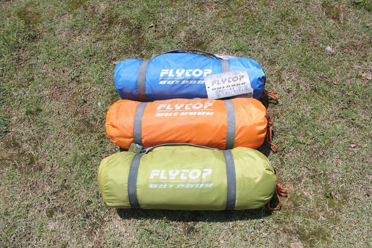 Colorful camping tents by Flytop in blue, orange, and green on grass, ideal for outdoor enthusiasts.