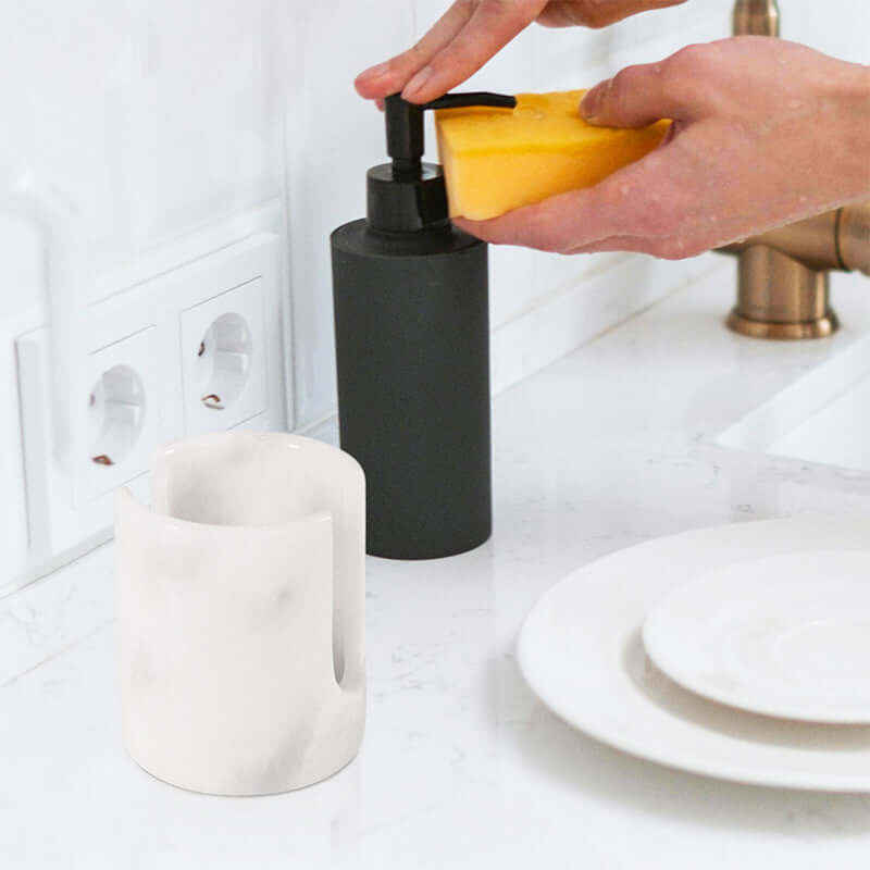 3.5" marble sponge holder next to a soap dispenser at a kitchen sink, keeping sponges organized and accessible.