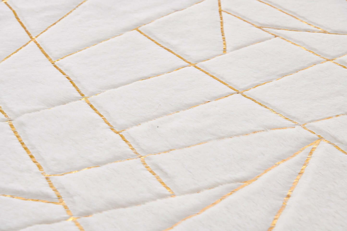 Close-up of a white and gold abstract shag area rug with geometric patterns.