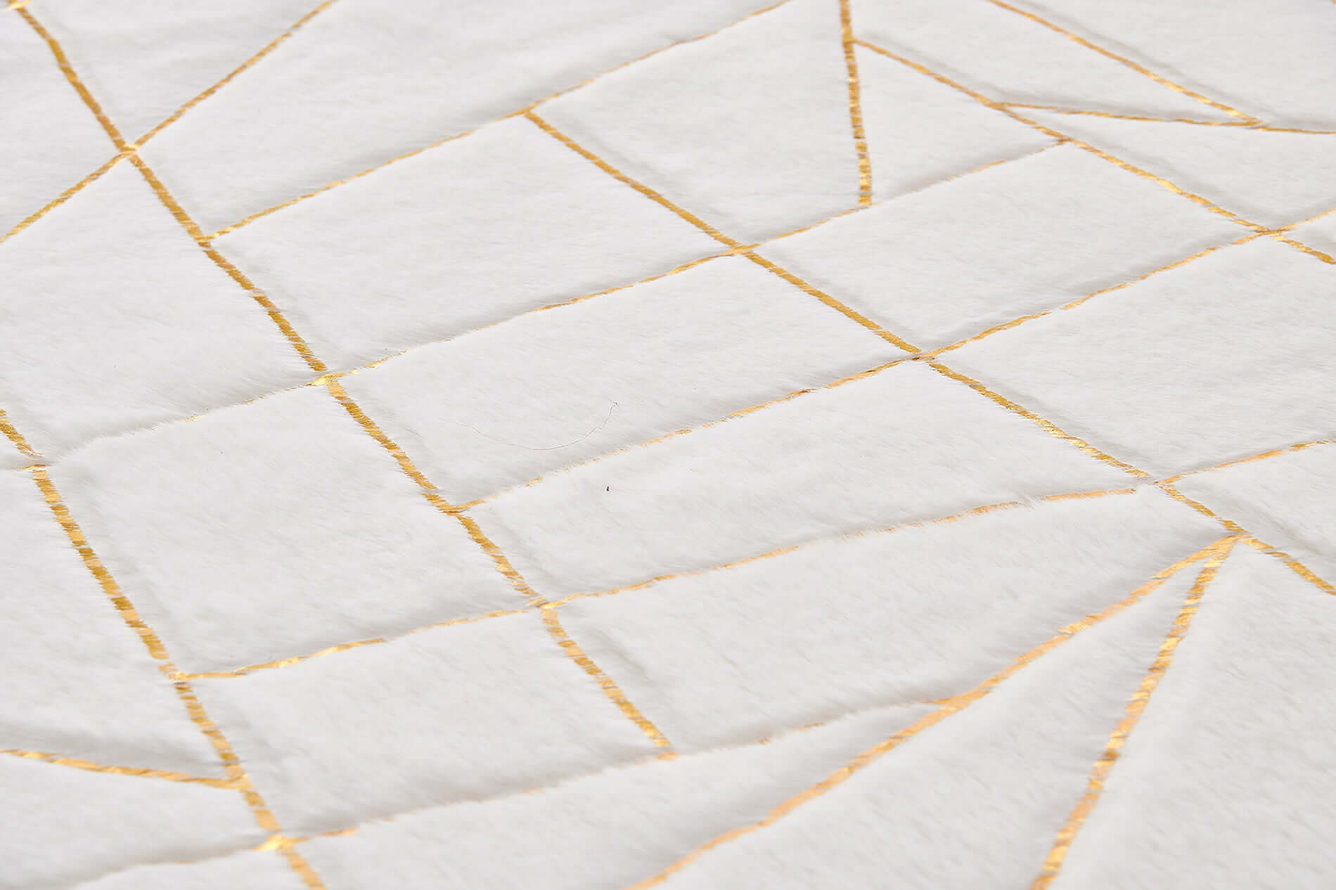 Close-up of a white and gold abstract shag area rug with geometric patterns.