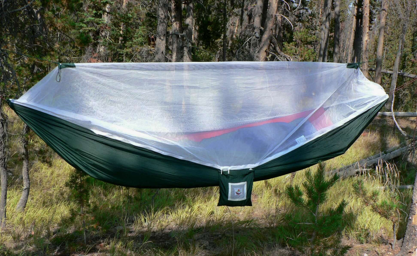 Mosquito Free hammock with white netting set in a forest, offering comfort and protection from pests.