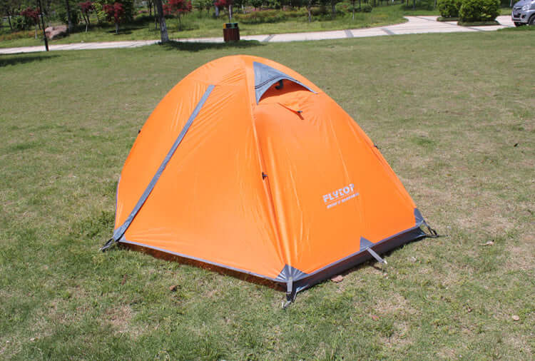 Orange outdoor camping tent set up on grass, designed for rainproof and ultra-light camping in high mountain conditions.
