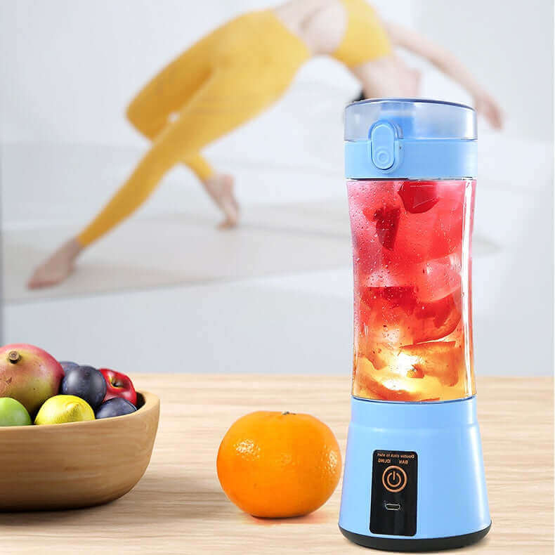 Portable electric fruit juicer blending colorful ingredients with fresh fruits on a kitchen counter.
